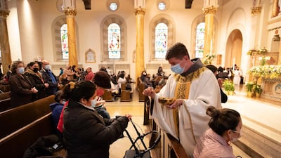 Rev Russels Governale serves communion during a Spanish-language Easter service at St Bartholomew Roman Catholic Church in New York on Sunday. AP Photo