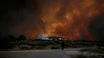 Smoke rises behind a house as a wildfire burns near the village of Varnavas, north of Athens, Greece. Alkis Konstantinidis / Reuters