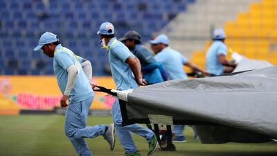 Ground staff covering the pitch due to rain at the match between Maratha Arabians and Karnataka Tuskers. Pawan Singh / The National