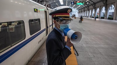 A railway worker speaks in a loudspeaker next to the first official train departing from a railway station after the lockdown was lifted in Wuhan, China. EPA