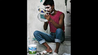 One of several dozen construction labourers who live in the compound shaves in a communal area.