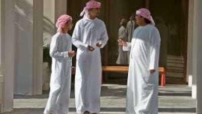 Mohamed al Saqqaf, left, Sameer al Jaberi and Abdullah al Obaidli, right, chat in a corridor of Abu Dhabi Men's College.