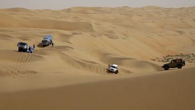 Racers from teams KAMAZ-Master from Russia (left) and Team SiXT of the Ukraine with Vadym Nesterchuk and Konstantin Meshcheryakov (centre) stop to contemplate the course as safety officials watch (right) during the third stage of the Abu Dhabi Desert Challenge in the Empty Quarter in Abu Dhabi on Tuesday, April 5, 2011. Pawel Dwulit / The National