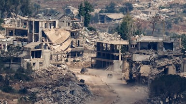 Israeli military vehicles drive past destroyed buildings in Lebanon, seen from northern Israel. Reuters