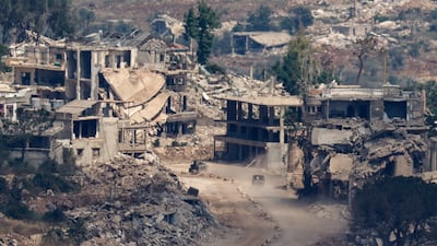 Israeli military vehicles drive past destroyed buildings in Lebanon, seen from northern Israel. Reuters