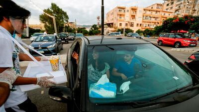A man wearing a face shield brings popcorn to a couple seated in a car to watch a movie at a drive-in cinema in a park in Lebanon's northern coastal city of Byblos. AFP