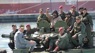President Nicolas Maduro raises his fist from an amphibious tank as he poses for photos alongside his wife Cilia Flores. AP