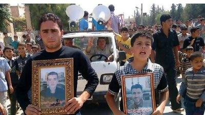 Syrian protesters hold portraits for their dead relatives killed in recent violence as they march in Maaret Harma village yesterday.
