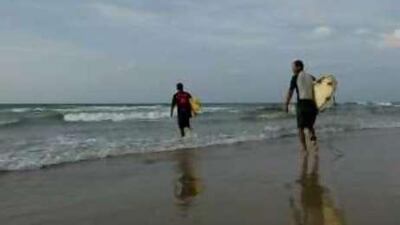 Mohammad Abu Jayyad and Ahmed Abu Hasiera try to catch some waves in Gaza.