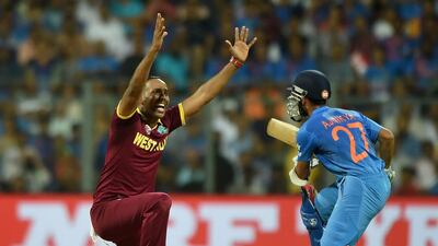 West Indies bowler Samuel Badree (L) appeals successfully for the wicket of India’s Rohit Sharma during the World T20 cricket tournament semi-final match between India and West Indies at The Wankhede Cricket Stadium in Mumbai on March 31, 2016. / AFP / PUNIT PARANJPE