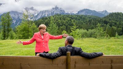 Angela Merkel talks to US President Barack Obama, who sits on a bench facing the Wetterstein mountains during a G7 meeting at Elmau Castle in Elmau, Germany, June 8, 2015. EPA