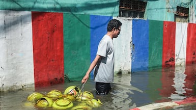 A shopkeeper drags liquefied petroleum gas cylinders through high floodwater, after heavy rain caused a river to burst its banks, in Bandung, West Java, Indonesia. AFP