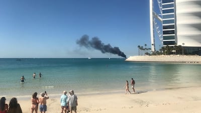 Beach-goers look on with concern as smoke billows from the ship. The National