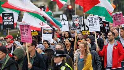People display placards and Iranian flags as they attend the 'Hands off Iran' march to the US Embassy in London. EPA