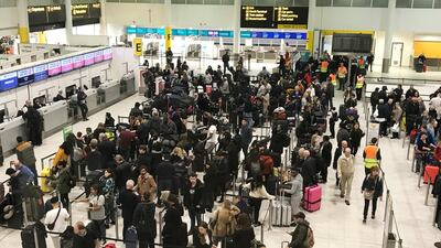 Passengers wait to check in at Gatwick Airport in England where drone sightings caused hours of delays in December. AP