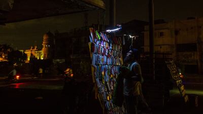 A vendor sells decorations for motorbike registration plates under an emergency light at his makeshift stall in Karachi. All photos: Bloomberg