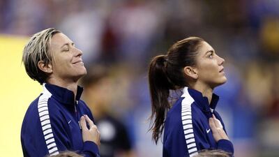 U.S. forward Abby Wambach, left, smiles during the playing of the national anthem before the team's international friendly soccer match against China in New Orleans, Wednesday, Dec. 16, 2015. At right is goalie Hope Solo. (AP Photo/Gerald Herbert)
