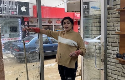 Gulshah Aktan, 28, shows how flood water rose to shoulder height in her family's electronics repair shop in the Ayazaga district of northern Istanbul. Lizzie Porter / The National