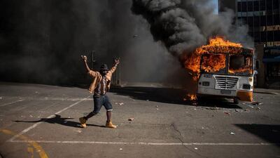 A student gestures near a burning bus during clashes with riot police following a protest over University tuition fees in Johannesburg. South African student protesters and police clashed in renewed violence in Johannesburg as attempts to re-open Wits University descended into running battles on campus. Protesters throwing rocks were dispersed by riot police using tear gas, rubber bullets and stun grenades as pressure ratchets up on campuses across the country over tuition fees. AFP