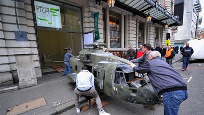 An Agusta Westland 1/3 scale model helicopter used in the film Skyfall is loaded in to the London Film Museum.