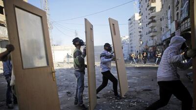 Palestinian protesters take cover behind doors during clashes with Israeli border police at a checkpoint between the Shuafat refugee camp and Jerusalem on November 6, 2014. Ammar Awad / Reuters