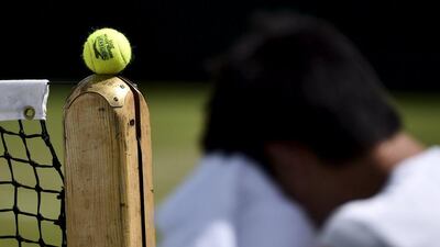 A tennis ball is seen balancing on the net during a practice session prior to the 2015 Wimbledon tournament starting on Monday. Toby Melville / Reuters / June 27, 2015