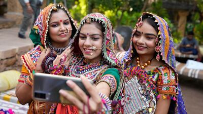Women in colourful traditional attire take a selfie as they practice the garba. AP