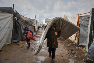 Salam Musa, 9, carries a mattress as he walks between tents after rainfall at a temporary camp in Deir al-Balah on November 14. AP