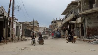 Syrians ride their motorcycles through a damaged neighbourhood in the town of Binnish in Idlib province. AFP