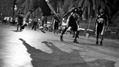 A Black team member attempts to block a Blue team member from scoring.