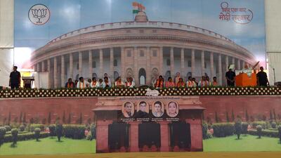 Indian Prime Minister Narendra Modi (2nd R) gives a speech on a stage with the backdrop of the Indian Parliament Building at a rally in Amreli, some 250km from Ahmedabad, on April 18, 2019. More than 157 million of the 900 million electorate are eligible to cast ballots on the second of seven days of voting in the world's biggest election. / AFP / SAM PANTHAKY