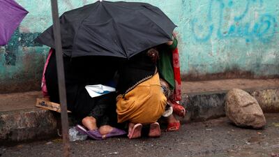 Yemeni girls gather under an umbrella to shelter from the rain in Sanaa, Yemen. EPA