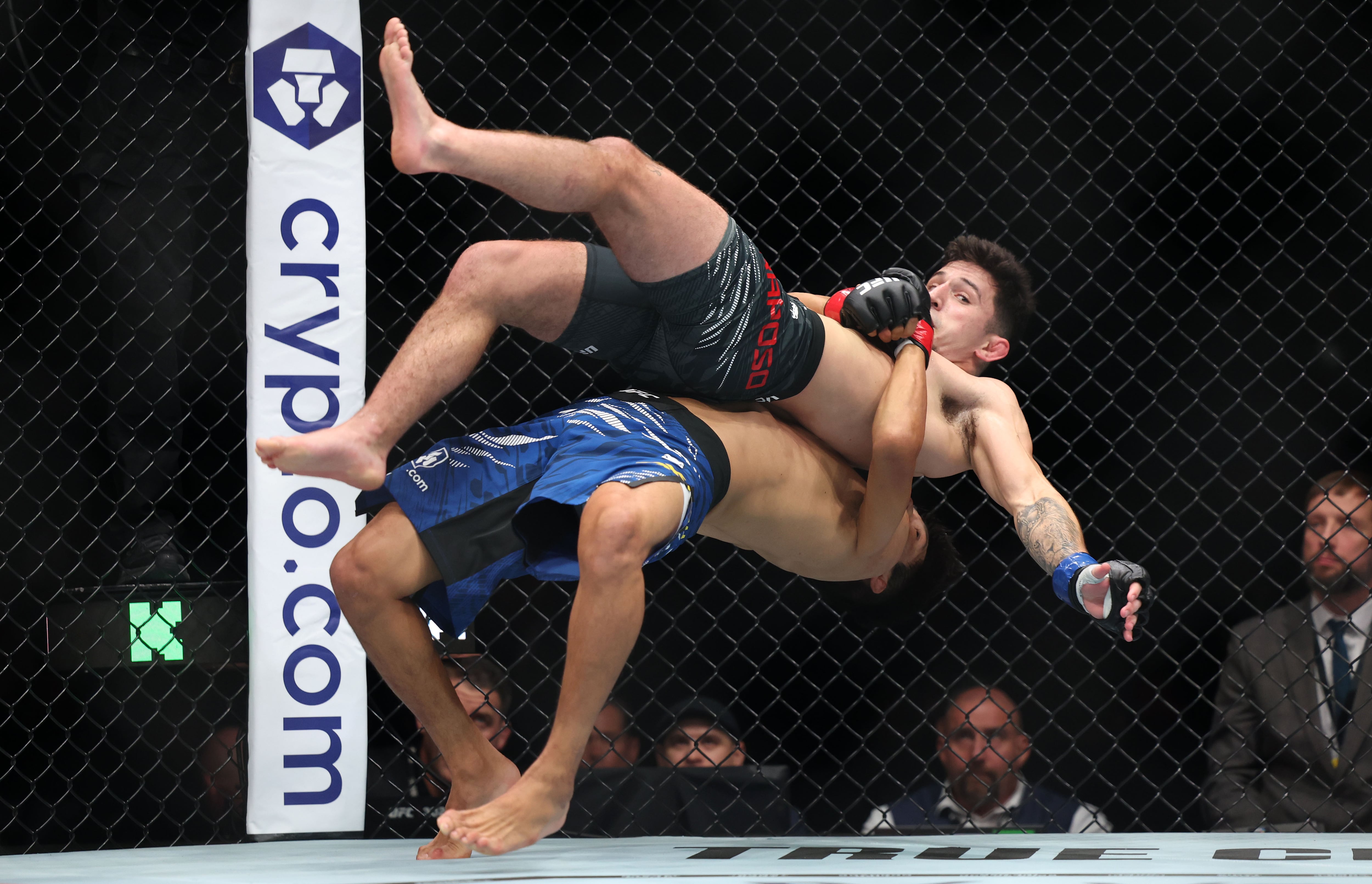 Mitch Raposo (black shorts) gets taken to the mat by Azat Maksum (blue shorts). The American would win the catchweight bout by decision.