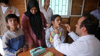 A medic consulting patients at a mobile clinic in a Syrian refugee camp. AFP / Caritas International