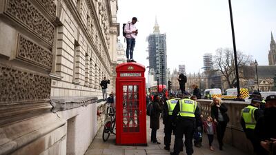 A man stands on a telephone booth during an anti-lockdown demonstration amid the coronavirus disease (COVID-19) outbreak in London. Reuters