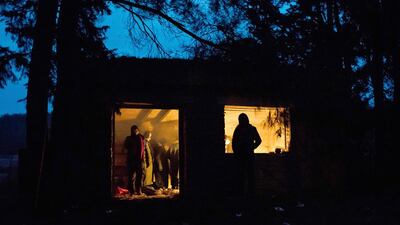 Refugees huddle around a fire in a building in a forest near the Macedonia border. They will try to enter the country before moving to Europe. Lazar Simeonov for The National