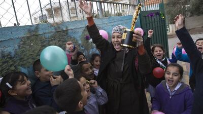 Palestinian teacher Hanan Al Hroub holds her Global Teacher trophy as her pupils greet her back to the Samiha Khalil school in Al Bireh, just outside Ramallah, on March 20, 2016. Photo by Heidi Levine For The National