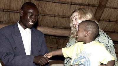 Madonna holds her adopted son, David, as they meet with the boy's biological father, Yohane Banda, left, on Monday at a lodge where the pop star is staying in Lilongwe, Malawi.