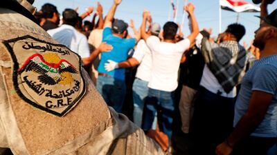 A member of the Iraqi anti-riot police stands guard as dozens shout slogans and wave national flags during a demonstration outside the local government headquarters in the southern city of Basra. AFP