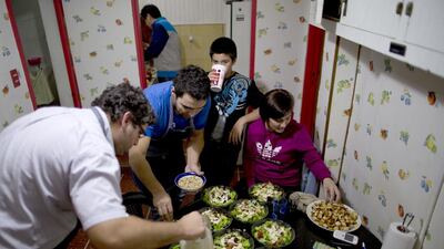 Chefs Martin Arrojo, left, and Ezequiel De La Torre, second from left, prepare salad for a Cookapp gathering in Buenos Aires. Natacha Pisarenko / AP Photo