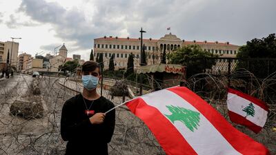 A protester waves a Lebanese flag alongside a barbed wave set up to protect the government palace in downtown Beirut. Lebanese Prime Minister Saad Hariri announced a series of economic measures adopted by the government and approved the 2020 budget without any new taxes.EPA