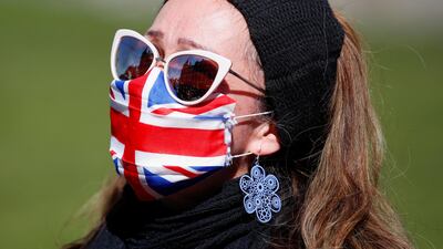 A woman wearing a Union Jack face mask stands outside Windsor Castle during the funeral of Britain's Prince Philip, husband of Queen Elizabeth, who died at the age of 99. REUTERS / Peter Cziborra