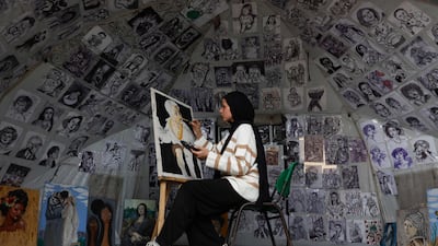 A displaced Palestinian teenager paints a portrait inside her tent at UNRWA's Al Rimal school shelter, in northern Gaza. AFP