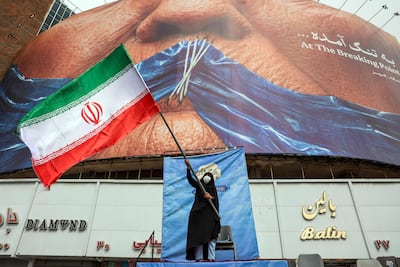 A woman waves an Iranian flag in front of an anti-US billboard at Valiasr Square in Tehran. AFP