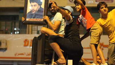 Iraqis celebrate with a picture of Moqtada Al Sadr in Baghdad on May 14, 2018, as the Shiite cleric's alliance emerged as the leader in preliminary results from the general election. Ahmad Al Rubaye / AFP