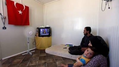 A Syrian family watches television at a refugee camp called ”Container City” on the Turkish-Syrian border in Oncupinar, southern Turkey. Soldiers, as well as refugees, are increasingly seeking refuge in Turkey.
