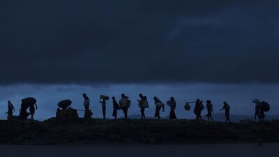 Rohingya refugees walk across paddy fields at dusk in Gundum, Bangladesh, after crossing the border from Myanmar on September 09, 2017. Dan Kitwood / Getty Images