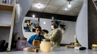 A hairdresser wearing a protective suit gives customer a haircut in Sanaa, Yemen. EPA