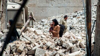 TOPSHOT - An Iraqi woman carries a child as she walks through the rubble in the Old City of Mosul on July 2, 2017, during the offensive to retake the city from Islamic State (IS) group fighters. More than eight months since the country's forces launched a gruelling operation to retake Mosul, IS has gone from fully controlling the city to holding a few neighbourhoods on its western side. / AFP PHOTO / Fadel SENNA