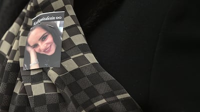 A mourner wears a photograph of Ms Siloni at her funeral. Several mourners were pictured with photographs of the jewellery designer pinned on their clothes. Ozan Kose / AFP Photo.